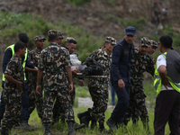 Rescuers from Nepal's security agencies are carrying charred bodies of a dead passenger retrieved from a passenger aircraft of Saurya Airlin...