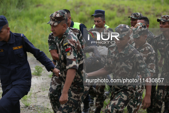 Rescuers from Nepal's security agencies are carrying charred bodies of a dead passenger retrieved from a passenger aircraft of Saurya Airlin...