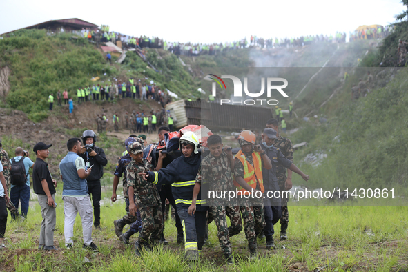 Rescuers from Nepal's security agencies are carrying charred bodies of a dead passenger retrieved from a passenger aircraft of Saurya Airlin...