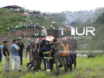 Rescuers from Nepal's security agencies are carrying charred bodies of a dead passenger retrieved from a passenger aircraft of Saurya Airlin...