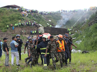 Rescuers from Nepal's security agencies are carrying charred bodies of a dead passenger retrieved from a passenger aircraft of Saurya Airlin...