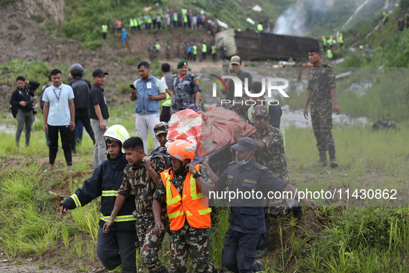 Rescuers from Nepal's security agencies are carrying charred bodies of a dead passenger retrieved from a passenger aircraft of Saurya Airlin...