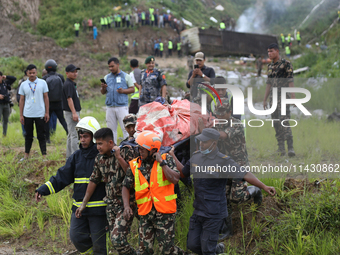 Rescuers from Nepal's security agencies are carrying charred bodies of a dead passenger retrieved from a passenger aircraft of Saurya Airlin...