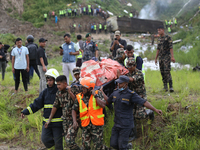 Rescuers from Nepal's security agencies are carrying charred bodies of a dead passenger retrieved from a passenger aircraft of Saurya Airlin...