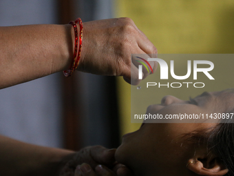 A health worker is administering a polio vaccine drop to a child in Patan, Lalitpur, on July 24, 2024. The Nepal government is starting a fo...