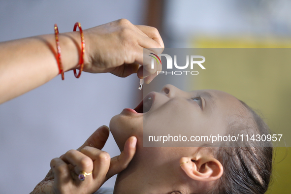 A Nepali health worker is administering 'OPV' to a child during a door-to-door immunization campaign following the government's special immu...