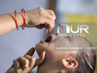 A Nepali health worker is administering 'OPV' to a child during a door-to-door immunization campaign following the government's special immu...