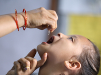 A Nepali health worker is administering 'OPV' to a child during a door-to-door immunization campaign following the government's special immu...