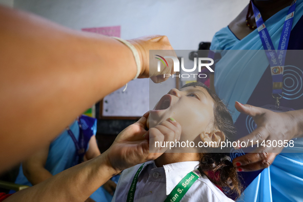 A Nepali health worker is administering 'OPV' to a child during a door-to-door immunization campaign following the government's special immu...