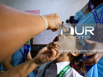 A Nepali health worker is administering 'OPV' to a child during a door-to-door immunization campaign following the government's special immu...