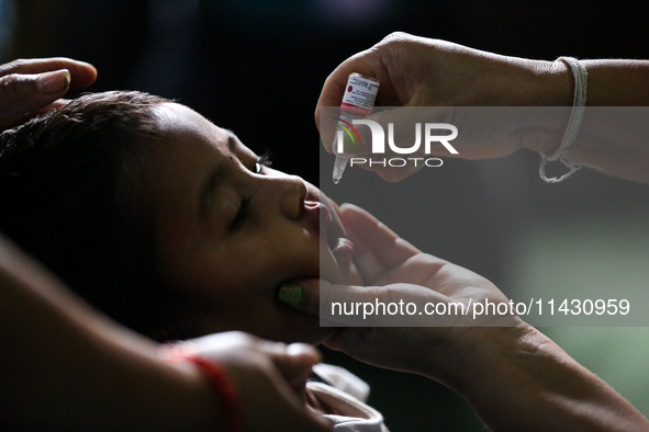 A Nepali health worker is administering 'OPV' to a child during a door-to-door immunization campaign following the government's special immu...