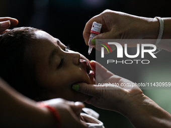 A Nepali health worker is administering 'OPV' to a child during a door-to-door immunization campaign following the government's special immu...