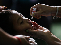 A Nepali health worker is administering 'OPV' to a child during a door-to-door immunization campaign following the government's special immu...