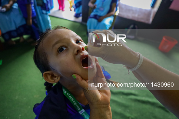 A Nepali health worker is administering 'OPV' to a child during a door-to-door immunization campaign following the government's special immu...