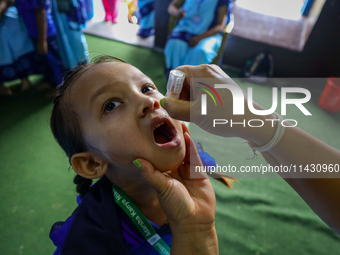 A Nepali health worker is administering 'OPV' to a child during a door-to-door immunization campaign following the government's special immu...