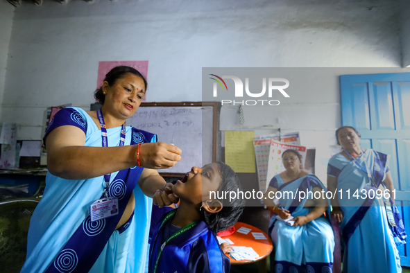 A Nepali health worker is administering 'OPV' to a child during a door-to-door immunization campaign following the government's special immu...