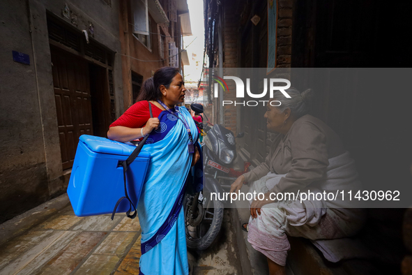 A Nepali health worker is inquiring with an elderly member of a family to ensure the children below 5 years are being administered with 'OPV...