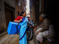 A Nepali health worker is inquiring with an elderly member of a family to ensure the children below 5 years are being administered with 'OPV...