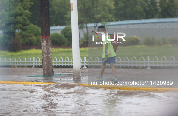 A child is walking on a flooded road after heavy rain in Sanmenxia, China, on July 24, 2024. 