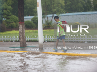 A child is walking on a flooded road after heavy rain in Sanmenxia, China, on July 24, 2024. (