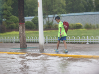 A child is walking on a flooded road after heavy rain in Sanmenxia, China, on July 24, 2024. (