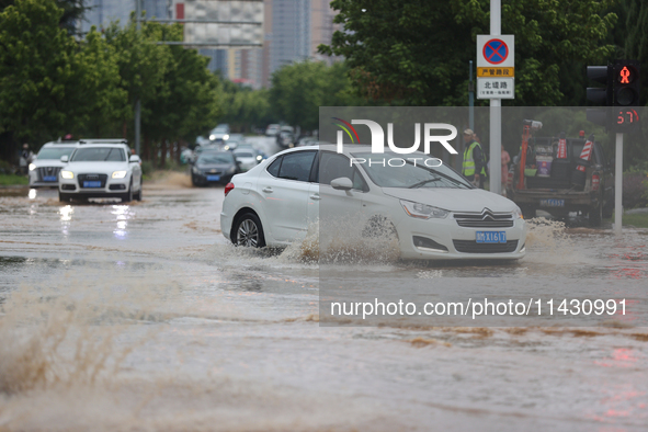 Vehicles are running on a flooded road after heavy rain in Sanmenxia, Henan province, China, on July 24, 2024. 