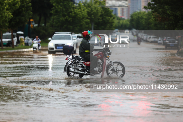 Vehicles are running on a flooded road after heavy rain in Sanmenxia, Henan province, China, on July 24, 2024. 