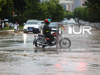 Vehicles are running on a flooded road after heavy rain in Sanmenxia, Henan province, China, on July 24, 2024. (