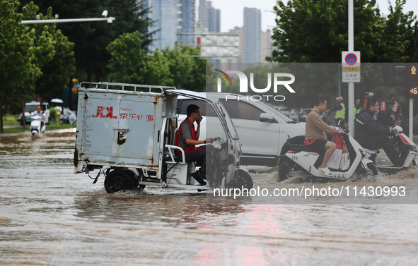 Vehicles are running on a flooded road after heavy rain in Sanmenxia, Henan province, China, on July 24, 2024. 