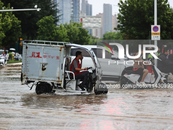 Vehicles are running on a flooded road after heavy rain in Sanmenxia, Henan province, China, on July 24, 2024. (