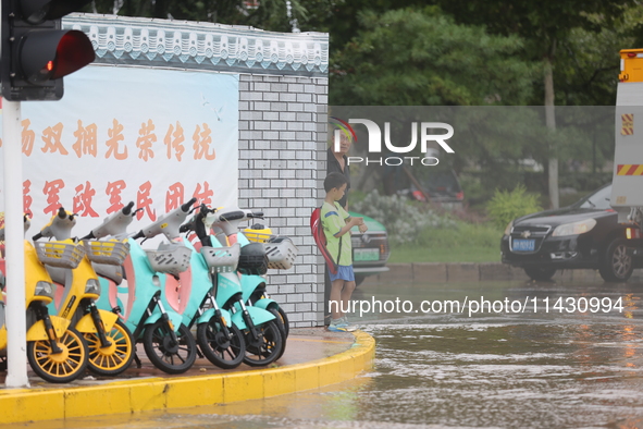 A child is walking on a flooded road after heavy rain in Sanmenxia, China, on July 24, 2024. 