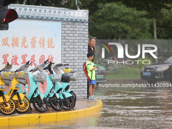 A child is walking on a flooded road after heavy rain in Sanmenxia, China, on July 24, 2024. (