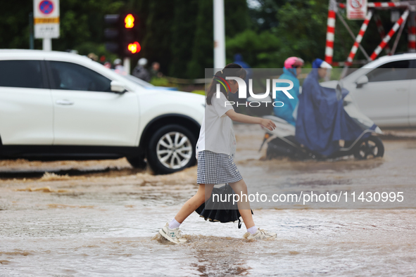 A pedestrian is walking on a flooded road after heavy rain in Sanmenxia, China, on July 24, 2024. 