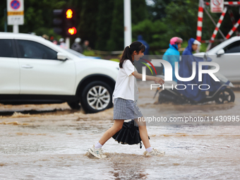 A pedestrian is walking on a flooded road after heavy rain in Sanmenxia, China, on July 24, 2024. (