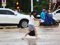 A pedestrian is walking on a flooded road after heavy rain in Sanmenxia, China, on July 24, 2024. (