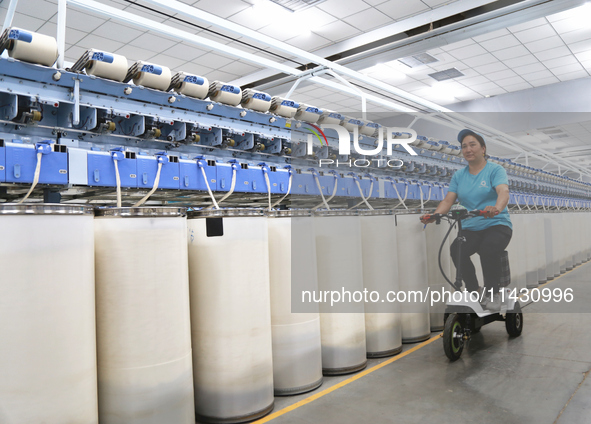 A worker is carrying out an inspection at a textile workshop in Aksu prefecture, Northwest China's Xinjiang Uygur autonomous region, on July...