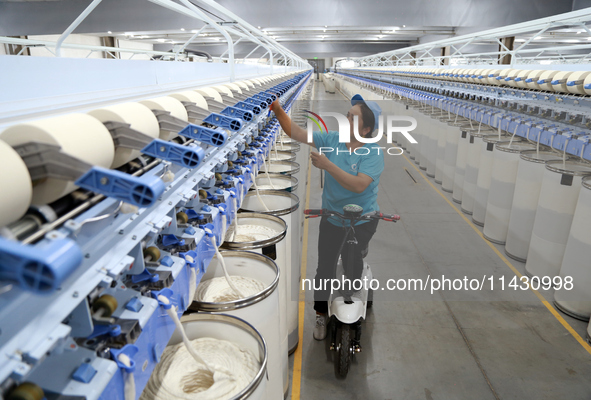 A worker is carrying out an inspection at a textile workshop in Aksu prefecture, Northwest China's Xinjiang Uygur autonomous region, on July...