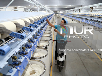 A worker is carrying out an inspection at a textile workshop in Aksu prefecture, Northwest China's Xinjiang Uygur autonomous region, on July...