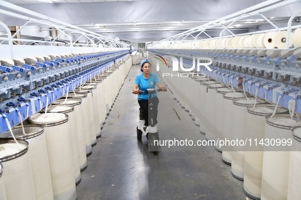 A worker is carrying out an inspection at a textile workshop in Aksu prefecture, Northwest China's Xinjiang Uygur autonomous region, on July...