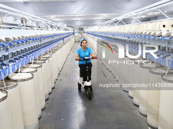 A worker is carrying out an inspection at a textile workshop in Aksu prefecture, Northwest China's Xinjiang Uygur autonomous region, on July...