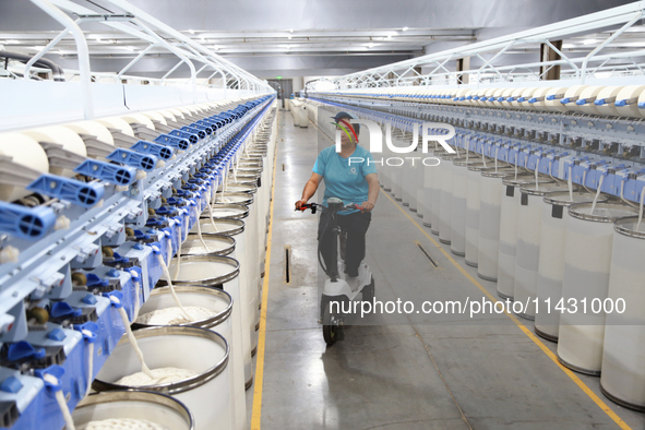 A worker is carrying out an inspection at a textile workshop in Aksu prefecture, Northwest China's Xinjiang Uygur autonomous region, on July...