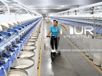 A worker is carrying out an inspection at a textile workshop in Aksu prefecture, Northwest China's Xinjiang Uygur autonomous region, on July...