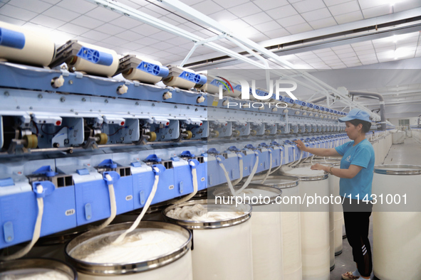 A worker is carrying out an inspection at a textile workshop in Aksu prefecture, Northwest China's Xinjiang Uygur autonomous region, on July...