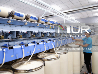 A worker is carrying out an inspection at a textile workshop in Aksu prefecture, Northwest China's Xinjiang Uygur autonomous region, on July...