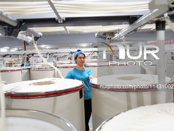 A worker is carrying out an inspection at a textile workshop in Aksu prefecture, Northwest China's Xinjiang Uygur autonomous region, on July...