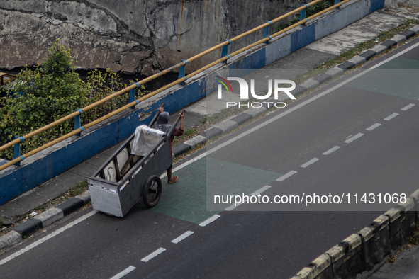 A scavenger is crossing a road in the central business district of Jakarta, Indonesia, on July 24, 2024. 