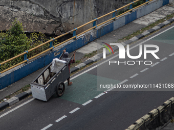 A scavenger is crossing a road in the central business district of Jakarta, Indonesia, on July 24, 2024. (