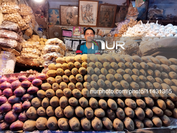 A person is selling potatoes, onions, and gingers inside a market in Kolkata, India, on July 24, 2024. 