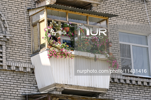 Flower pots are decorating a balcony of the five-storey apartment building at 44 Sobornyi Avenue as one of its sections is destroyed by the...