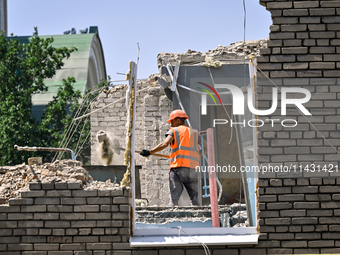 A builder is working to rebuild one of the sections of the five-storey apartment building at 44 Sobornyi Avenue that was destroyed by the Ru...